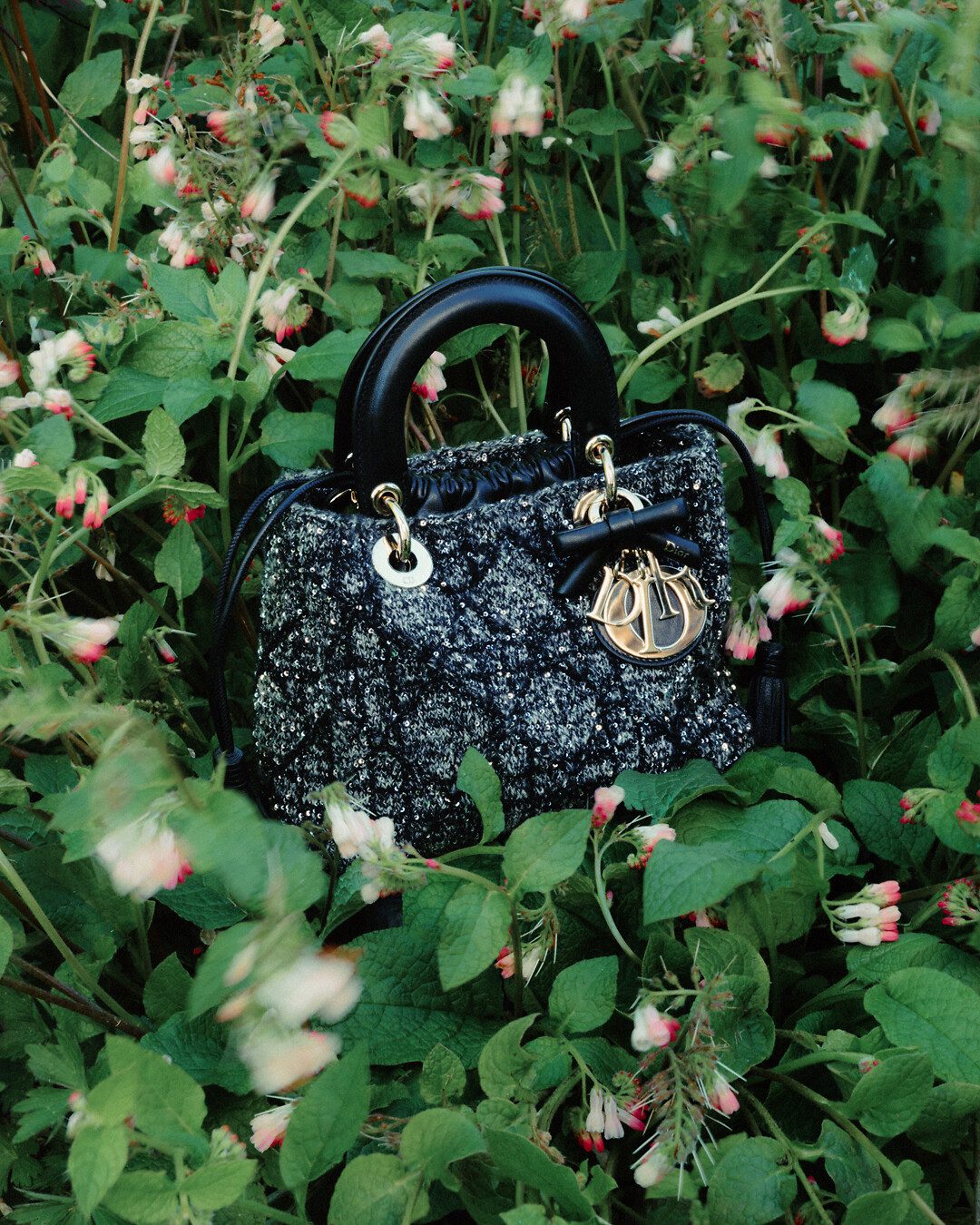 Bolsa Lady Dior preta entre folhagens