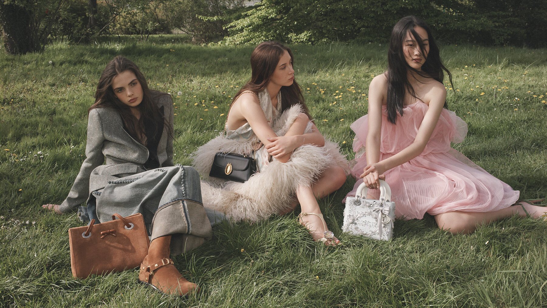 Três modelos na grama com bolsas Dior
